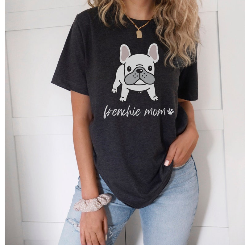 May include: A dark grey t-shirt featuring a white cartoon French bulldog and the text "frenchie mom" with a paw print.