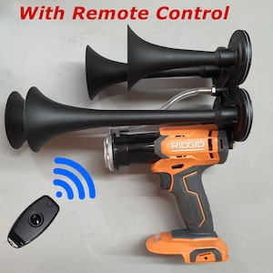 May include: A black air horn with a remote control. The air horn is attached to an orange and black power tool with the word "RIDGID" on it. The remote control is black and has a single button.