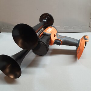 May include: A black air horn with two large black trumpet-shaped horns and a black and orange Ryobi air compressor attached to the horn.