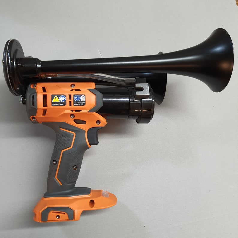 May include: An orange and black cordless power tool with a black air horn attached. The tool has a black trigger and a black handle. The air horn has a black trumpet-shaped nozzle.