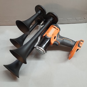 May include: A black air horn system with three horns and a Ridgid brand orange and black cordless air compressor.