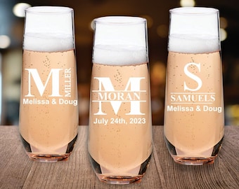 Op de afbeelding: Drie heldere champagneflutes met gepersonaliseerde gravures. De flutes zijn gevuld met een roze, mousserende drank. De gravures bevatten de namen "Miller", "Moran" en "Samuels" samen met de data "Melissa & Doug" en "24 juli 2023".