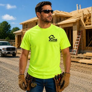 May include: A neon yellow short-sleeved t-shirt featuring a black logo on the left chest that reads Home Builder Custom Home Builders. The shirt is worn with blue denim jeans and tan work gloves, with a tape measure visible in a pocket.