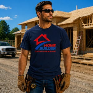 May include: A navy blue short-sleeved t-shirt featuring a red house icon and a blue swoosh graphic above the text "HOME BUILDER" and "CUSTOM HOME BUILDERS" in red and blue lettering, worn with tan leather work gloves and a tool belt.