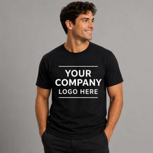 May include: A black short-sleeved crew neck t-shirt featuring white text centered on the chest that reads YOUR COMPANY LOGO HERE, framed by two horizontal white lines above and below the text, presented on a plain neutral background.