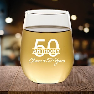 May include: A clear glass wine glass with the number 50 and the name Anthony printed on it. The text "Cheers to 50 Years" is also printed on the glass.