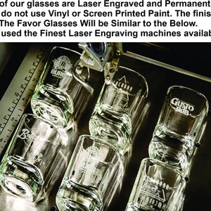 Puede incluir: Primer plano de seis vasos de chupito de vidrio transparente con varios logotipos grabados. Los vasos est&aacute;n siendo grabados con l&aacute;ser por una m&aacute;quina. El texto en los vasos dice "Burr", "Achbar", "Gusto BBQ" y "3".