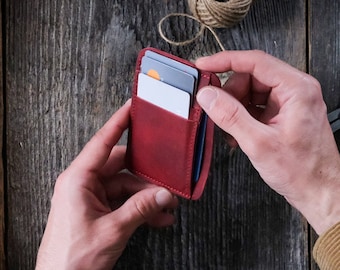 May include: A red leather wallet with multiple card slots. The wallet is open and has several cards inside.