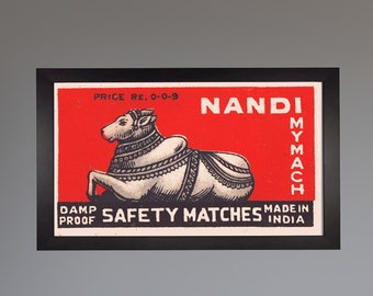 Puede incluir: Etiqueta vintage de caja de cerillas con fondo rojo que presenta una ilustración en blanco y negro de un toro Nandi. El texto "NANDI MYMACH" está impreso en negro en el lado derecho de la etiqueta. El texto "PRICE RE. 0-0-9 DAMP PROOF SAFETY MATCHES MADE IN INDIA" está impreso en negro en la parte inferior de la etiqueta.