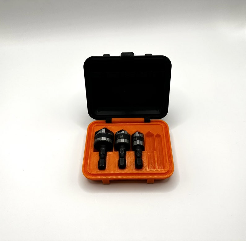May include: An orange plastic case with three drill bits and a black lid. The drill bits are labeled 5/16, 1/2, and 3/8.