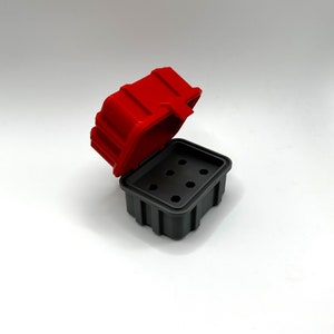 Op de afbeelding: Een rode en grijze plastic opbergdoos met een scharnierend deksel en meerdere compartimenten. Het deksel is open en de doos is leeg.