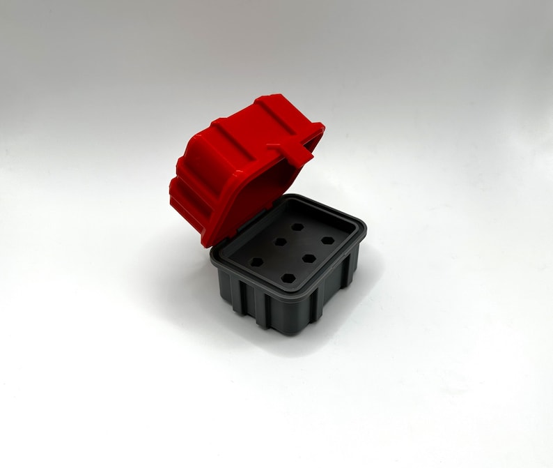 Op de afbeelding: Een rode en grijze plastic opbergdoos met een scharnierend deksel en meerdere compartimenten. Het deksel is open en de doos is leeg.