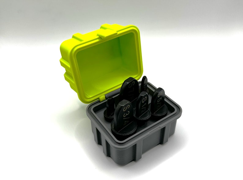 K&ouml;nnte beinhalten: Ein Satz schwarzer Werkzeuge mit Gr&ouml;&szlig;enmarkierungen, ordentlich in einem grauen Beh&auml;lter angeordnet. Der Beh&auml;lter befindet sich in einer leuchtend gelben Box mit limettengr&uuml;nem Innenraum. Die Box ist ge&ouml;ffnet und zeigt die Werkzeuge.