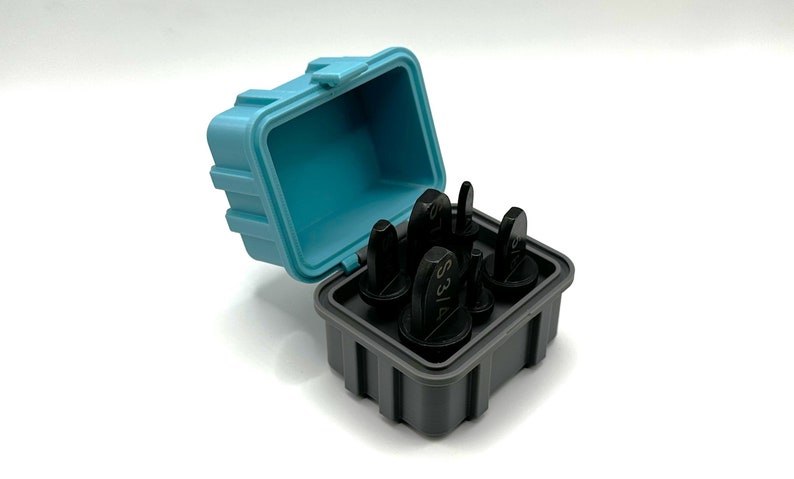 May include: A set of six black metal stamp punches in a gray and blue plastic case. The punches are labeled with the numbers 1, 2, 3, 4, 5, and 6.