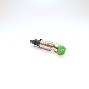 May include: A silver and black metal nozzle with a green plastic tip. The nozzle is designed for a pressure washer.