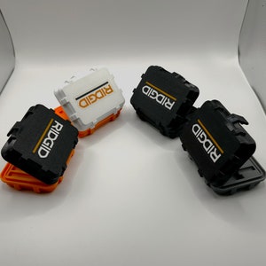 May include: Four small storage boxes with the word "RIDGID" printed on them. Two boxes are black and two are white.