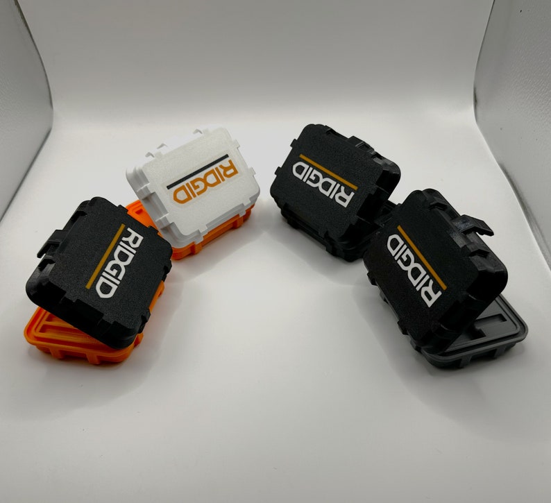 May include: Four small storage boxes with the word "RIDGID" printed on them. Two boxes are black and two are white.