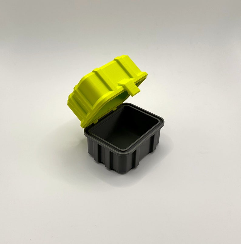 K&ouml;nnte beinhalten: Eine kleine, limegr&uuml;ne Aufbewahrungsbox mit einem schwarzen Deckel. Der Deckel ist ge&ouml;ffnet und die Box ist leer.