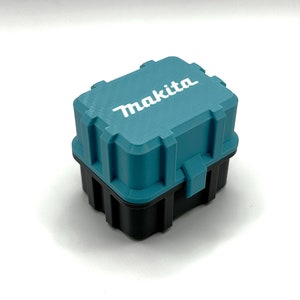 May include: A small teal blue plastic storage case with a black base. The case has a latch on the front and the word "Makita" printed in white on the top.