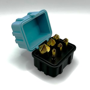 May include: A set of six gold-colored end mills in a black and blue plastic case. The case is open and the end mills are visible.