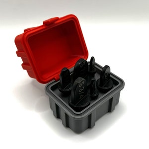 Op de afbeelding: Een set van zes zwarte metalen ponsgereedschappen in een rode en grijze kunststof koffer. De gereedschappen zijn gelabeld met verschillende maten, waaronder 3/16, 5/16, 7/16, 1/2, 5/8 en 3/4.