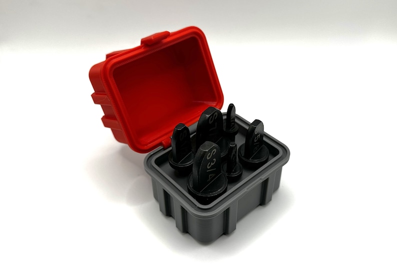 Op de afbeelding: Een set van zes zwarte metalen ponsgereedschappen in een rode en grijze kunststof koffer. De gereedschappen zijn gelabeld met verschillende maten, waaronder 3/16, 5/16, 7/16, 1/2, 5/8 en 3/4.