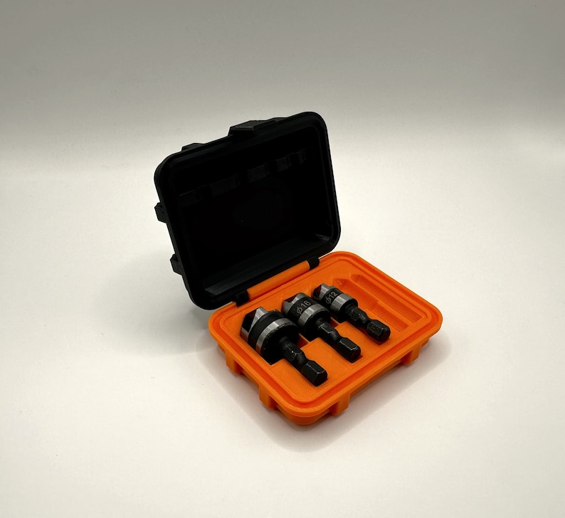 May include: A black plastic case with an orange interior holds three drill bits. The drill bits are labeled with sizes 1/8, 5/32, and 3/16.