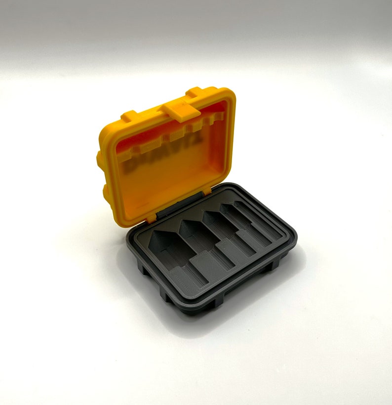 May include: A yellow plastic case with a black interior. The case has five slots for holding small items. The case is open and the slots are visible.