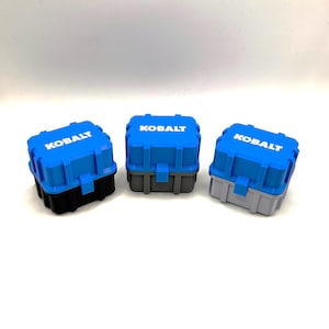 May include: Three small blue plastic storage boxes with the word "KOBALT" printed in white on the front. The boxes are in three different colors: black, gray, and light gray.