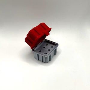 Op de afbeelding: Een rode en grijze plastic opbergdoos met een scharnierend deksel en meerdere compartimenten. Het deksel is open en de doos is leeg.