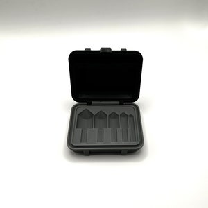 May include: A black plastic case with a gray interior, open to reveal five empty slots for holding small tools or other items.