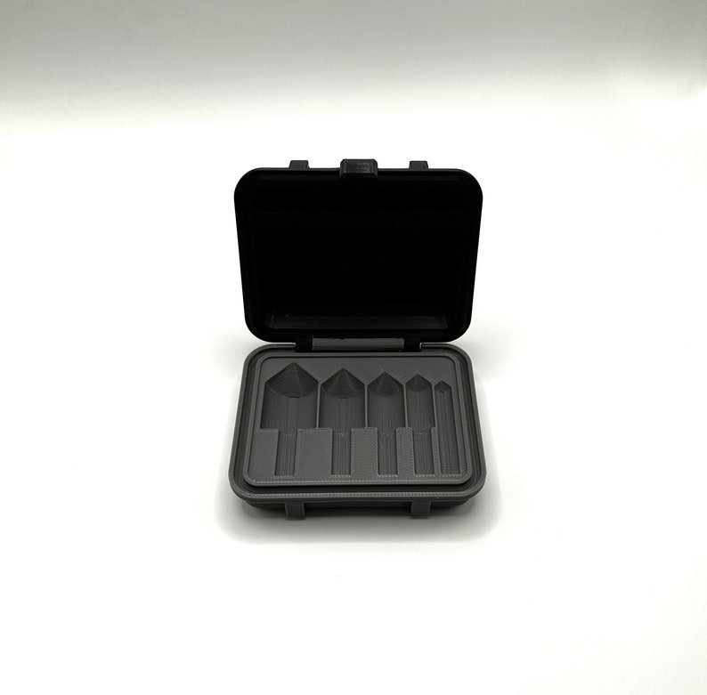 May include: A black plastic case with a gray interior, open to reveal five empty slots for holding small tools or other items.