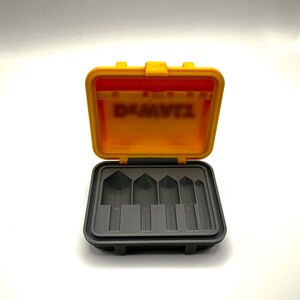May include: An open yellow plastic case with a gray interior. The case has six slots for holding small tools. The case has the word "DeWalt" printed on the inside of the lid.