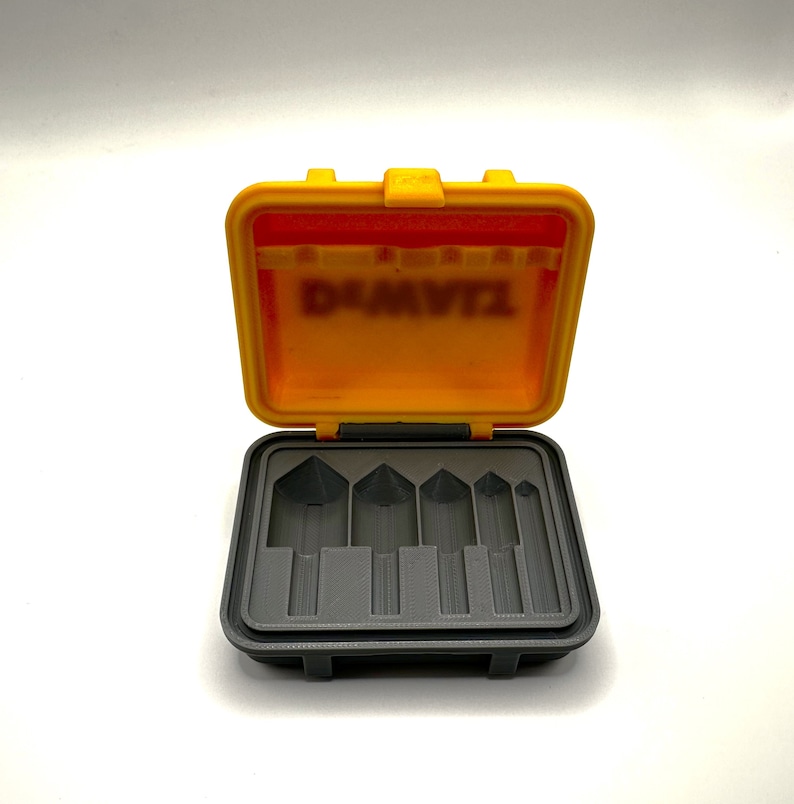 May include: An open yellow plastic case with a gray interior. The case has six slots for holding small tools. The case has the word "DeWalt" printed on the inside of the lid.