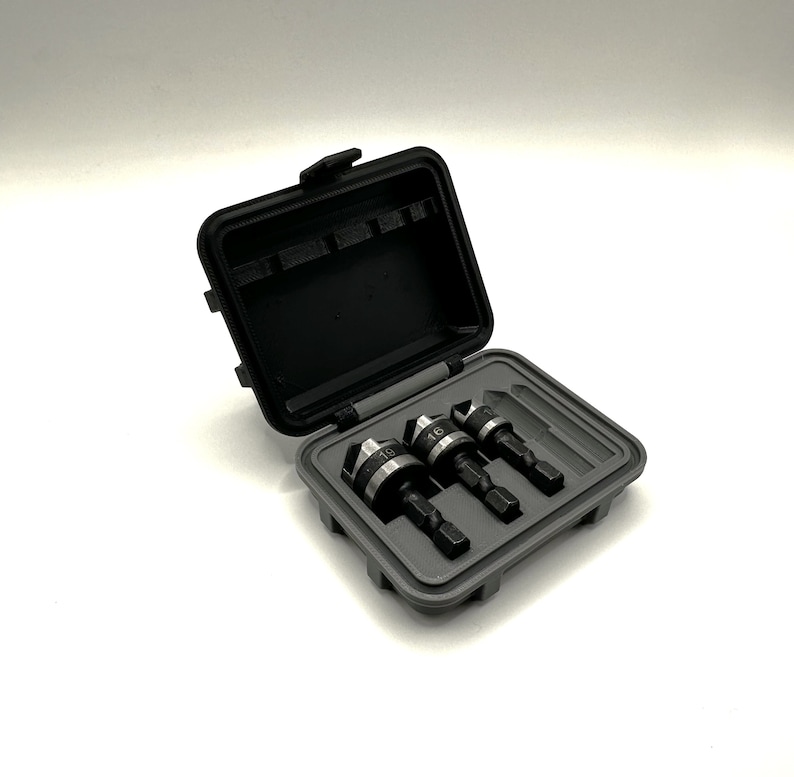 May include: A gray plastic case with four drill bits inside. The drill bits are black and silver with markings that say "16" and "15".