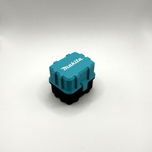 Pu&ograve; includere: Una piccola cassetta degli attrezzi in plastica blu turchese con la scritta "Makita" stampata in bianco sulla parte superiore.
