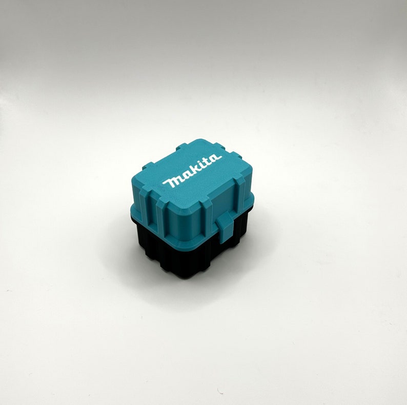 Pu&ograve; includere: Una piccola cassetta degli attrezzi in plastica blu turchese con la scritta "Makita" stampata in bianco sulla parte superiore.