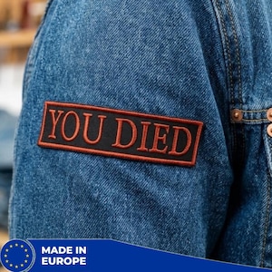 Può includere: Una tazza di ceramica bianca con manico nero e la scritta "But First, Coffee" in grassetto nero. La tazza è posta su uno sfondo sfocato, che suggerisce un'atmosfera accogliente. La tazza misura circa 10 cm di altezza.