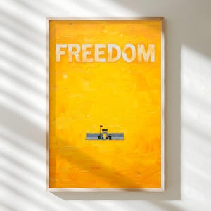 Könnte beinhalten: Gerahmter Kunstdruck mit einem leuchtend gelben Hintergrund und dem Wort "FREEDOM" in großen weißen Buchstaben. Eine kleine, detaillierte Struktur mit Flaggen befindet sich in der Mitte unten. Das Kunstwerk hat ein strukturiertes, gemaltes Aussehen.