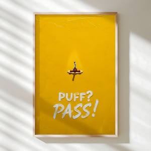May include: A framed artwork with a textured yellow background. A small, stylized object sits atop a small platform. The words "PUFF? PASS!" are written in white, stylized lettering below the object.