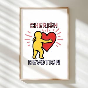 May include: Framed art print with a yellow figure hugging a red heart. The words "CHERISH" and "DEVOTION" are above and below the image. The artwork has a minimalist style with a white background and a light wood frame.