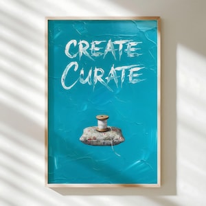 May include: A framed art print with the words "CREATE CURATE" in white script on a textured turquoise background. A floral print pillow with a wooden spool of white thread sits at the bottom of the image.