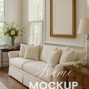 May include: A bright living room with a cream sofa, striped cushions, and a gold-framed picture. A wooden side table and a lamp are visible. The image has the text "Frame MOCKUP" overlaid. The room is well-lit with natural light.