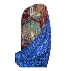 May include: A colorful silk scarf with a blue and floral pattern on one side and a multi-colored floral pattern on the other side. The scarf is folded in half and the blue side is facing the camera. The tag on the scarf reads "NectarStore".