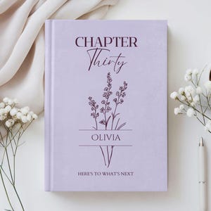 May include: A light purple hardback book featuring dark purple text that reads CHAPTER Thirty, OLIVIA, and HERE'S TO WHAT'S NEXT. The cover design includes a line art illustration of a floral sprig centred between the name and the final phrase.