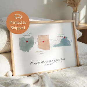 May include: A framed wall art print featuring watercolor maps of Ohio, Arizona, and Virginia connected by a dotted line with red hearts. The text reads: Home is wherever my family is, THE TAYLORS, Mansfield, Rimrock, and Front Royal.