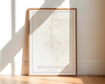 May include: A framed map print of Breckenridge, Colorado. The map is in black and white and shows the streets and landmarks of the town. The frame is a light brown wood.