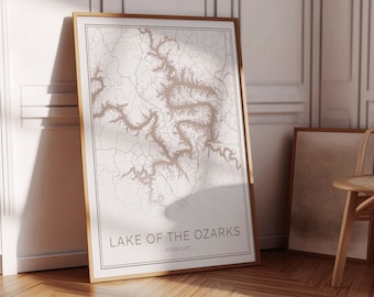 May include: A framed print of a map of Lake of the Ozarks in Missouri. The map is in a light brown color and is surrounded by a white border. The frame is a light wood color.