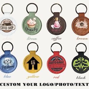 May include: Eight circular keyrings in different colours, each with a distinct design. Designs include a coffee cup, cupcake, nail polish bottle, floral arrangement, dog portrait, house logo, automotive graphic, and muscle graphic. The text "CUSTOM YOUR LOGO/PHOTO/TEXT" is at the bottom.