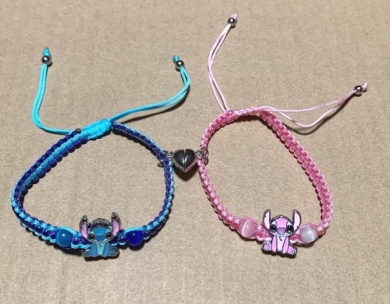 Puede incluir: Dos pulseras de la amistad con hilo azul y rosa, cuentas y dijes de Stitch de la pel&iacute;cula de Disney Lilo & Stitch.